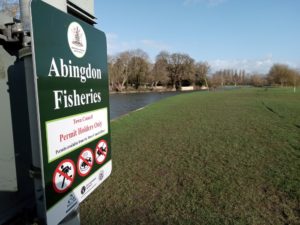 Looking past an Abingdon Fisheries sign downstream along the Thames on a sunny winter day